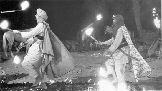 Doing the hot-foot two-step... Karamazovs juggle across hot coals on "Jewel of the Nile" set.